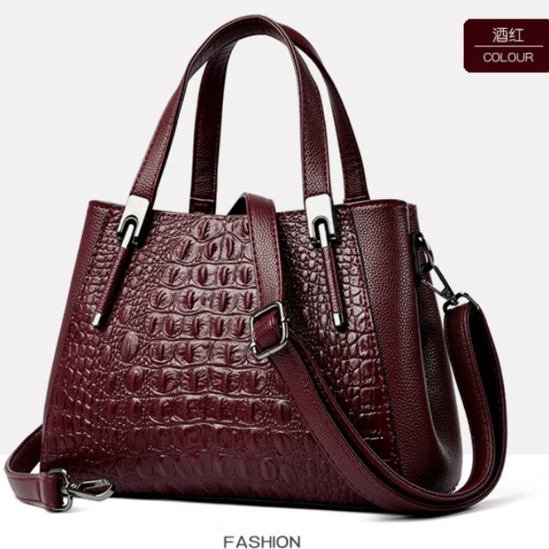 Wine red handbag with crocodile texture on a white background
