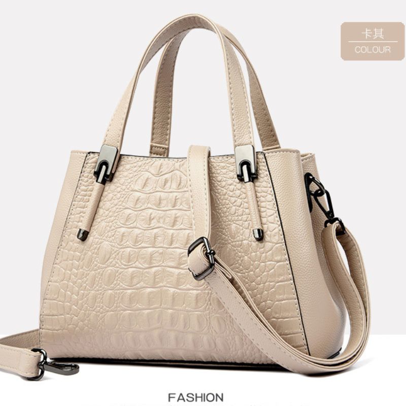 Beige handbag with crocodile texture on a light gray background