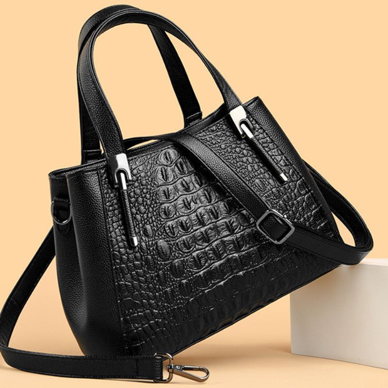 Black textured handbag with a strap on a beige background