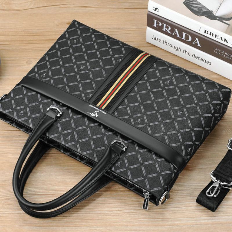 Black patterned handbag with a Prada book on a wooden surface