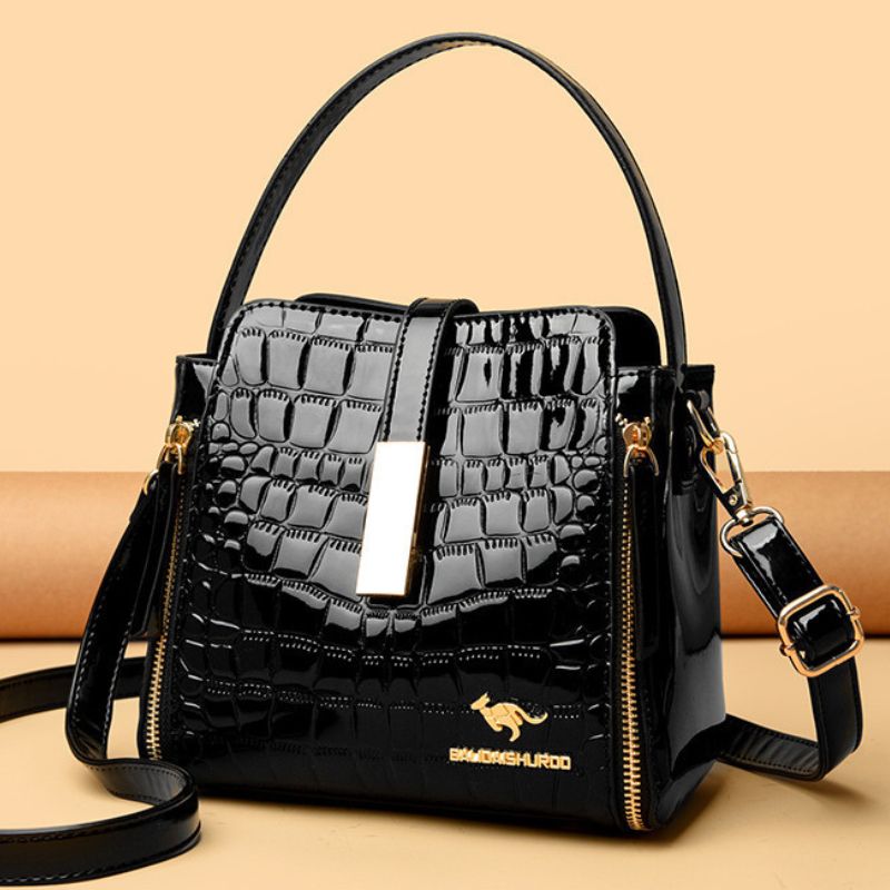 Black textured handbag with gold accents on a beige background