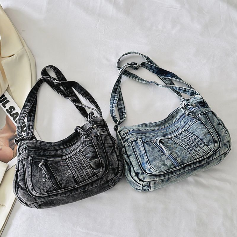 Two denim handbags, one black and one blue, on a white surface.
