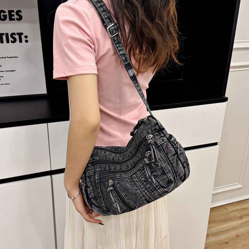 Person holding a black denim handbag indoors
