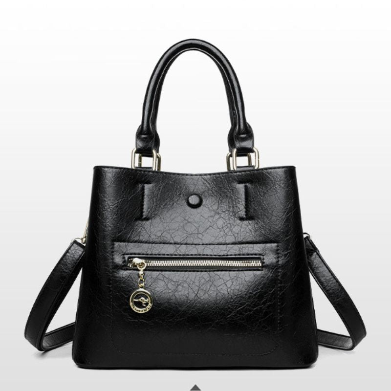 Black handbag with a strap on a light gray background