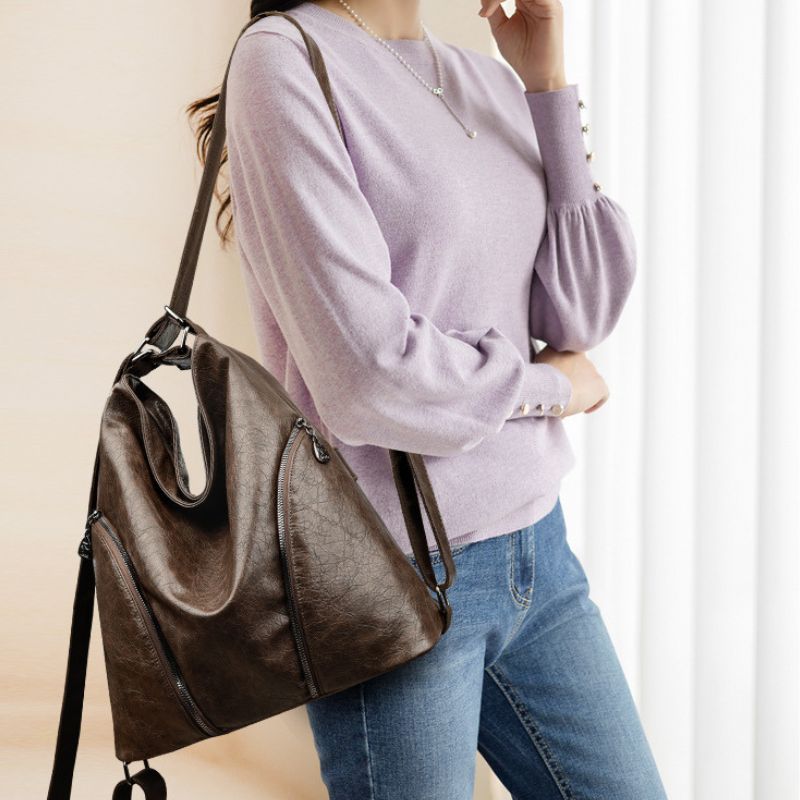 Person wearing a brown leather handbag with a neutral background