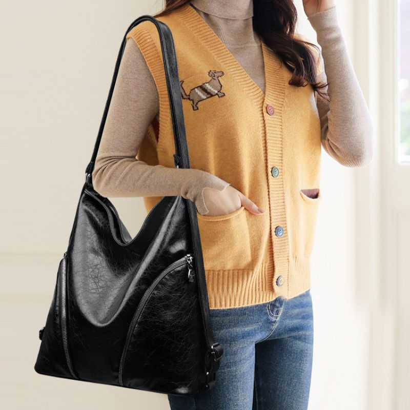 Person wearing a mustard yellow cardigan with a dog design, holding a black handbag.