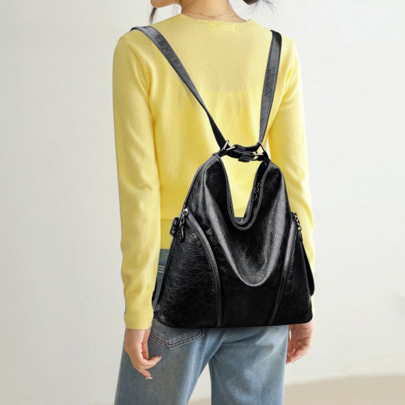 Person wearing a black backpack with a yellow shirt and light blue jeans on a plain background