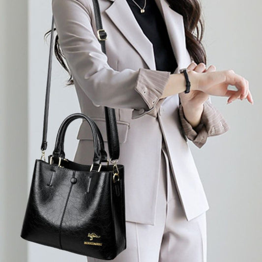 Person holding a black handbag with a neutral background