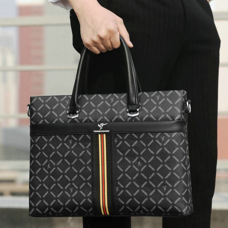 Black patterned handbag with a visible brand logo held by a person in a blurred outdoor setting.