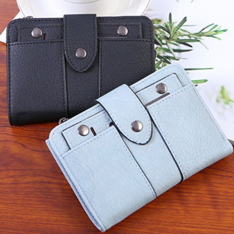 Black and light blue wallets on a wooden surface with a plant in the background