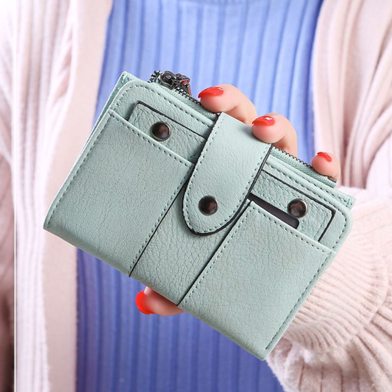 Light blue wallet held by a person with red nail polish against a blurred background