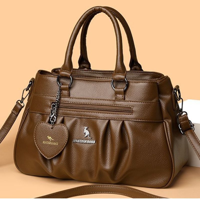 Brown handbag with a heart-shaped tag and visible brand logo on a beige background
