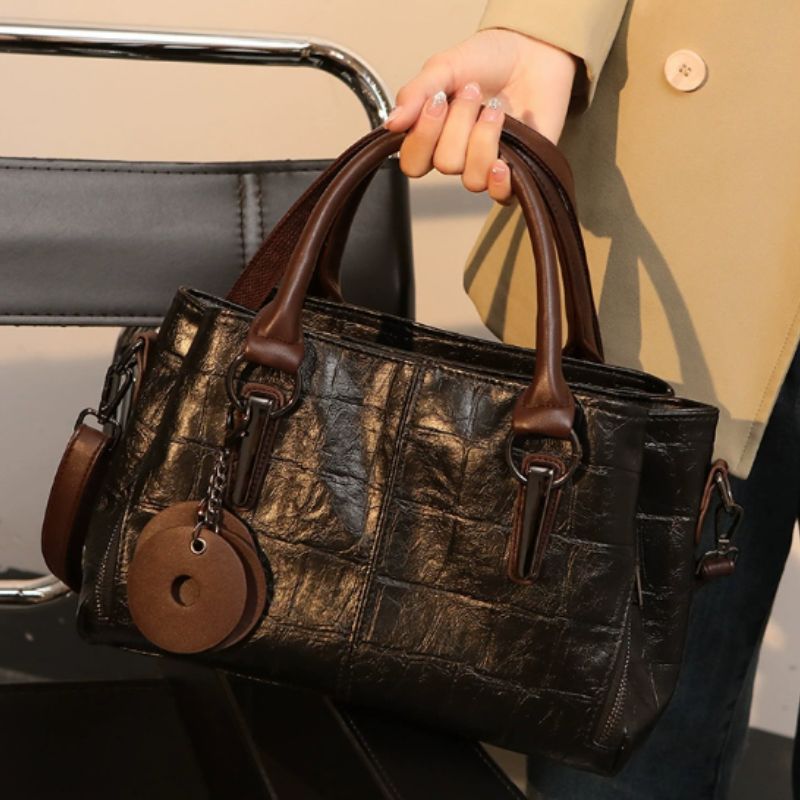 Brown leather handbag held by a person with a blurred background