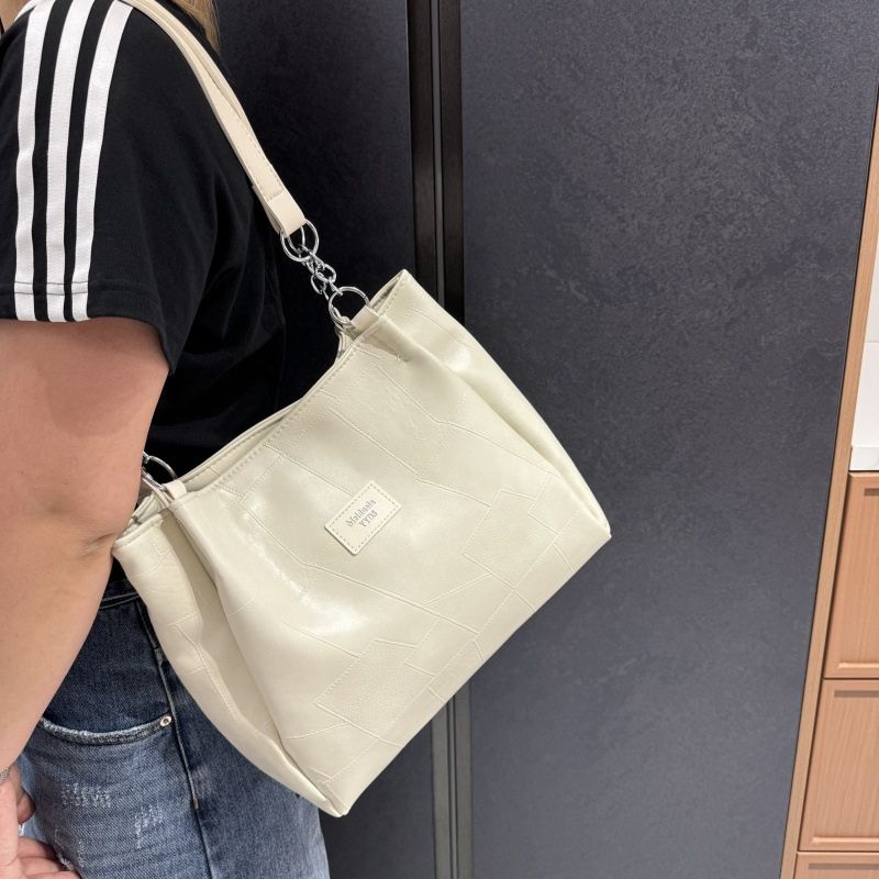 Person holding a beige handbag with a visible brand logo against a dark background