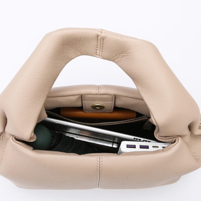 Beige handbag with a laptop and other items on a white background