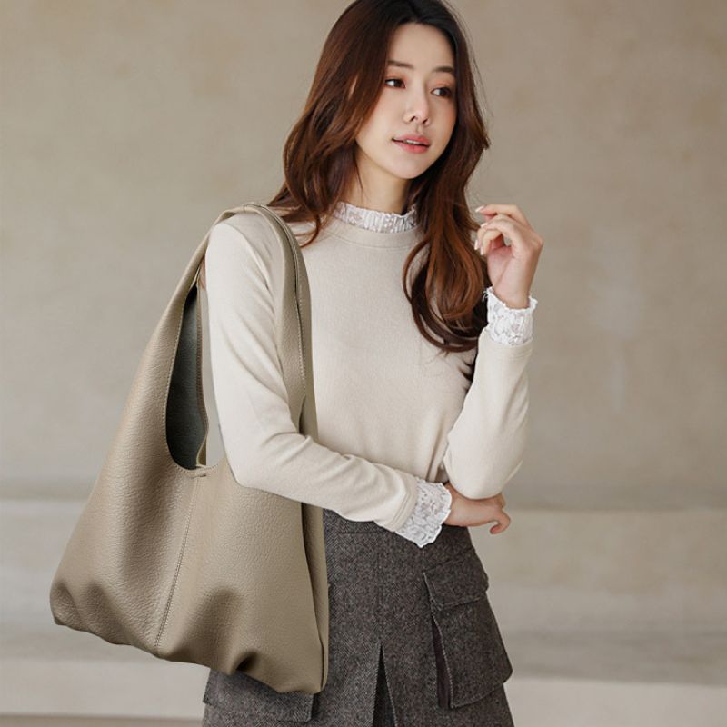 Woman holding a beige tote bag against a neutral background