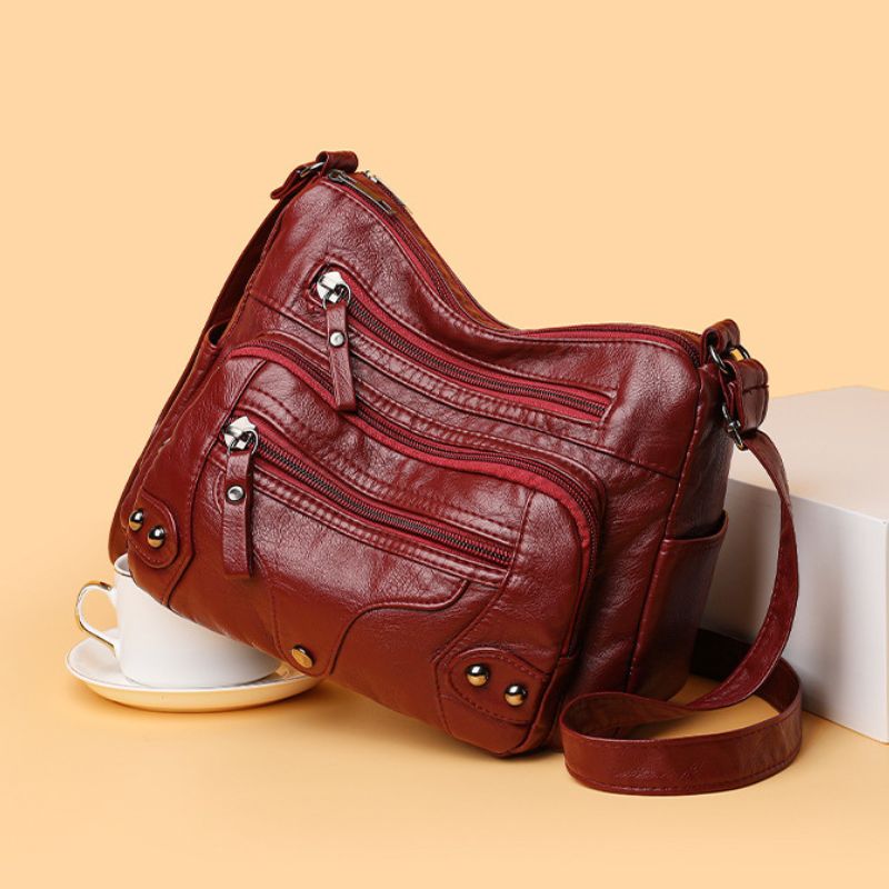 Brown leather handbag on a beige background with a cup and saucer.