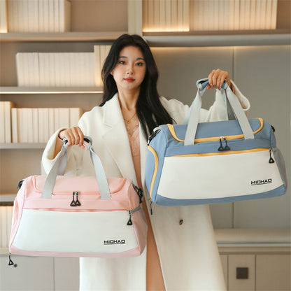 A woman holding two duffle bags in different colors, one pink and one blue, with white stripes and silver accents.