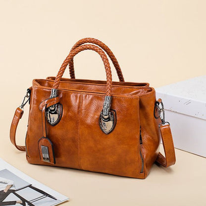 Brown leather handbag with braided handles on a beige surface