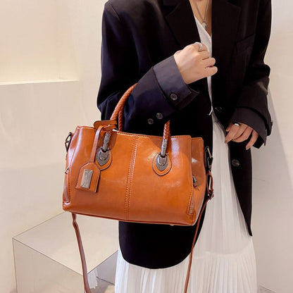 Person holding a brown leather handbag against a neutral background