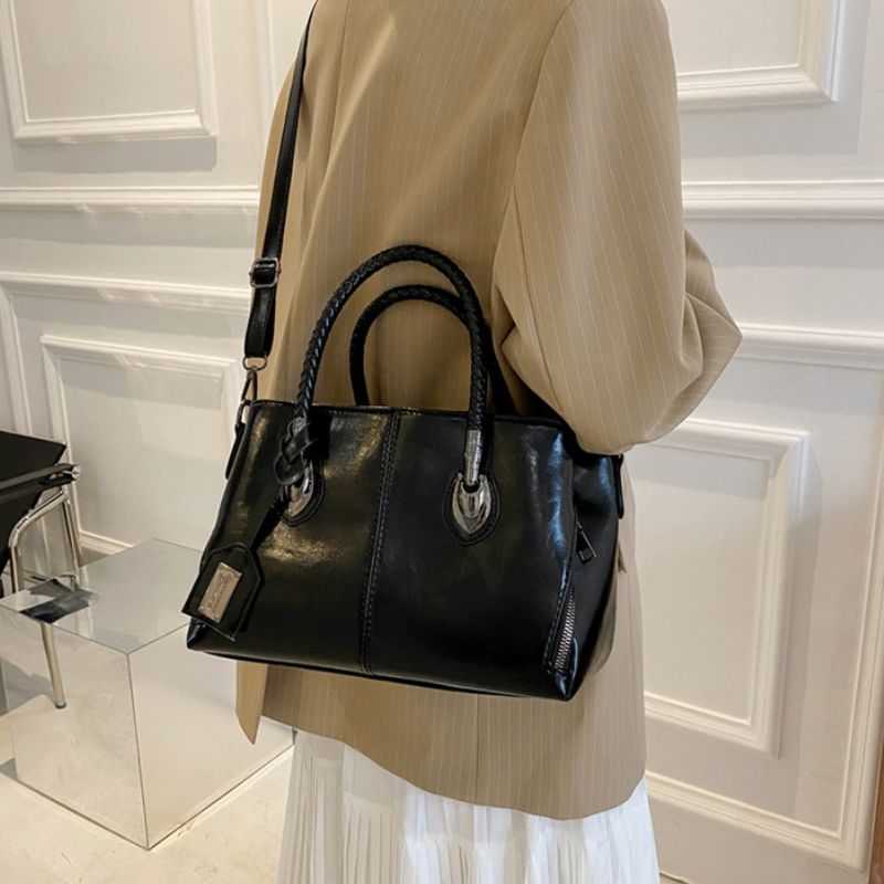 Person holding a black handbag in an indoor setting