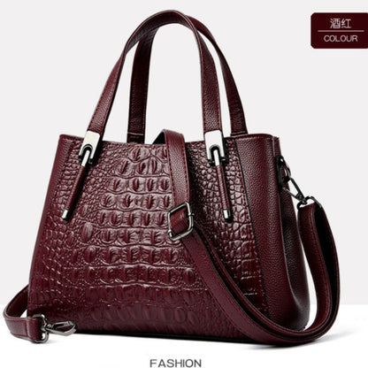 Wine red handbag with crocodile texture on a white background