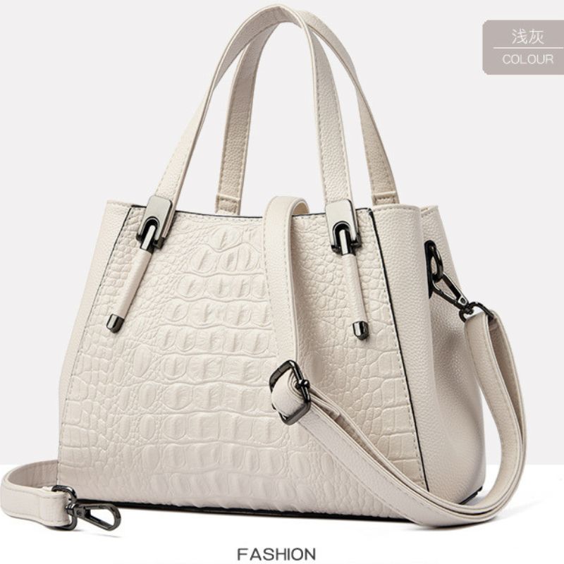 Beige handbag with crocodile texture on a white background