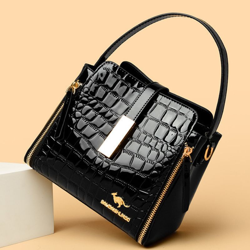 Black quilted handbag with gold accents on a beige background