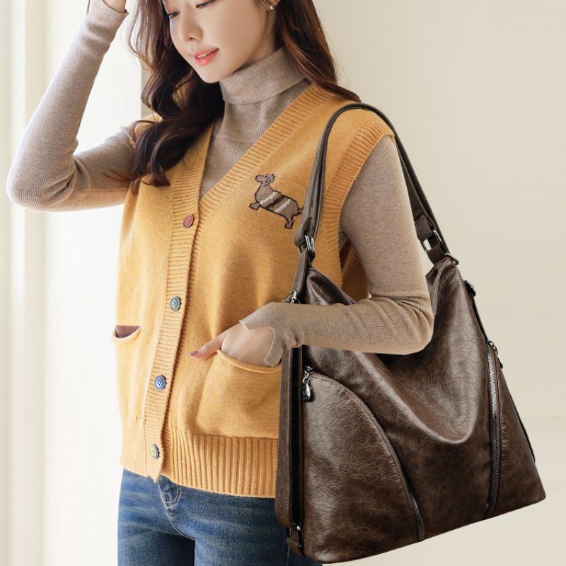 Woman wearing a mustard yellow cardigan with a dachshund design, holding a brown handbag.