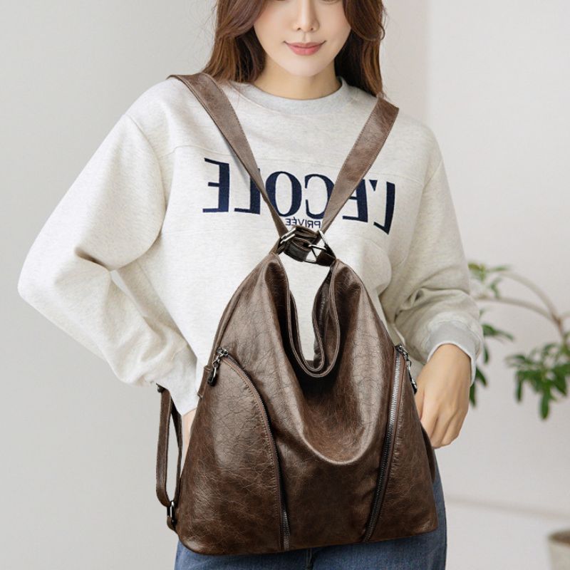 Woman wearing a brown backpack with a plain background
