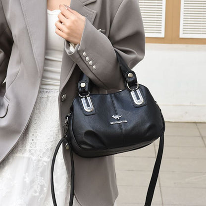 Person holding a black handbag with a visible brand logo indoors.