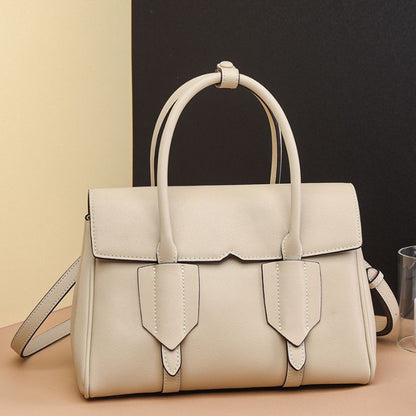 Beige handbag on a beige surface with a black background