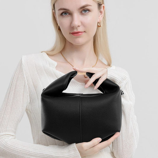 Woman holding a black leather handbag against a plain background