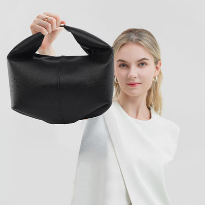 Woman holding a black handbag against a white background