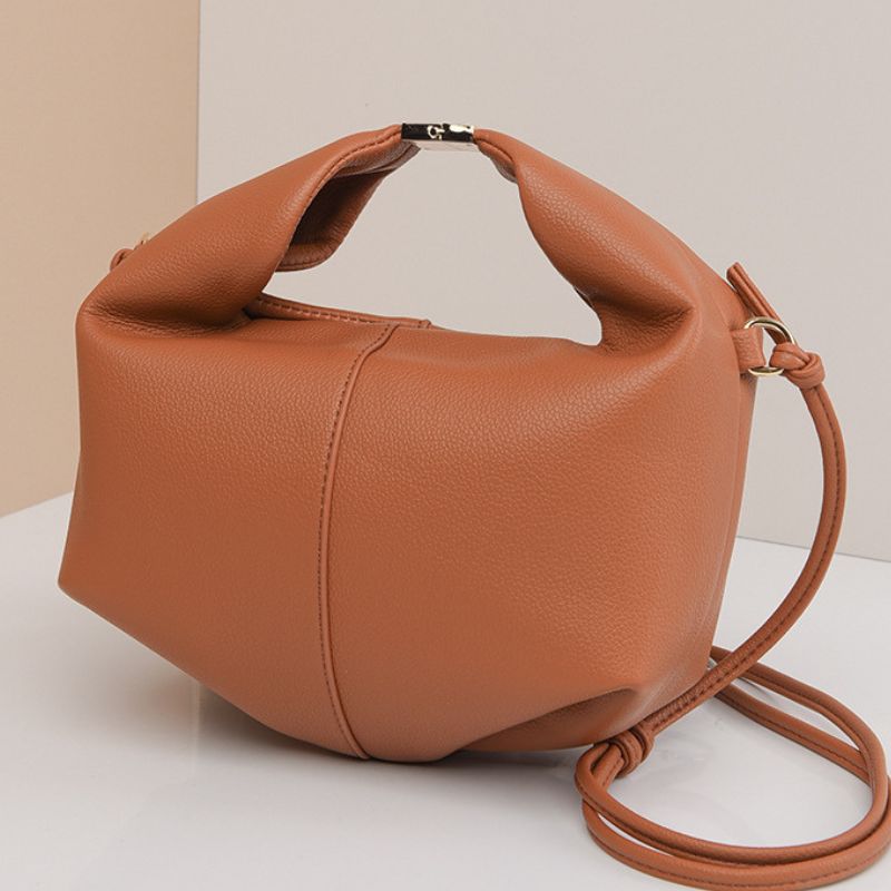Brown leather handbag with a strap on a light background