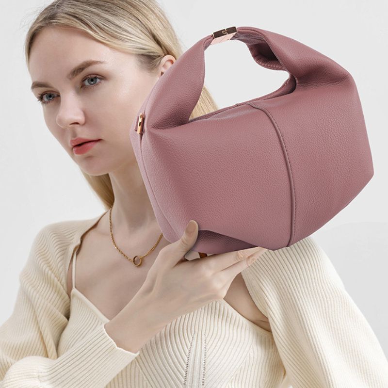 Woman holding a pink handbag against a plain background