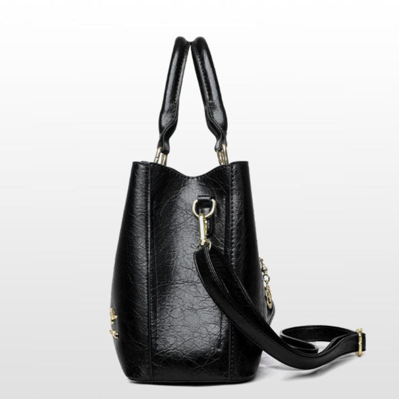 Black leather handbag with a strap on a light gray background