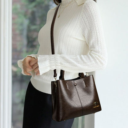 Person holding a brown handbag wearing a white sweater and dark pants.