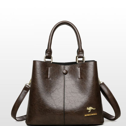 Brown leather handbag with a visible brand logo on a light gray background