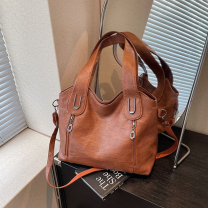 Brown leather handbag on a wooden surface with a blurred background