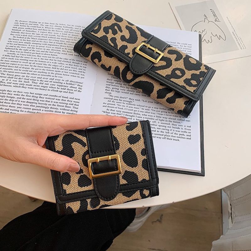 Leopard print wallet held by a hand on an open book