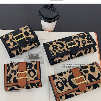 Leopard print wallets with gold buckles on a magazine page with a coffee cup in the background.