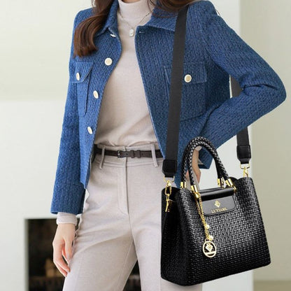 Person wearing a blue jacket holding a black handbag with gold accents.