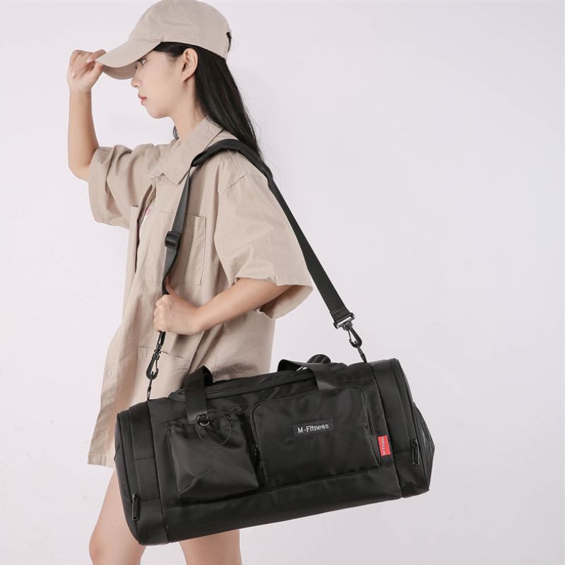 Person wearing a beige cap and holding a black duffel bag against a white background