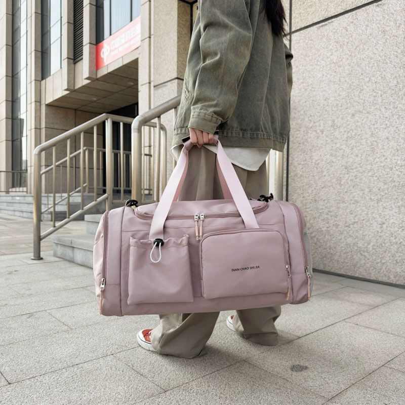 Person holding a pink duffel bag on a city street