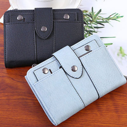 Black and light blue wallets on a wooden surface with a plant in the background