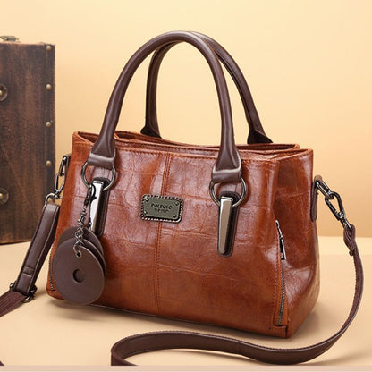 Brown leather handbag with a matching keychain on a beige background