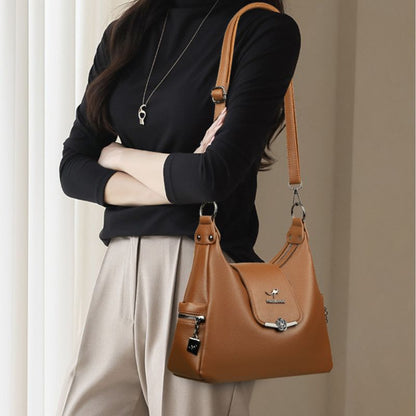 Person holding a brown leather handbag against a neutral background
