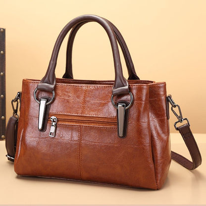 Brown handbag with silver zippers on a beige background