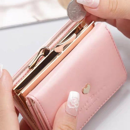 Pink wallet with gold accents being opened by a hand